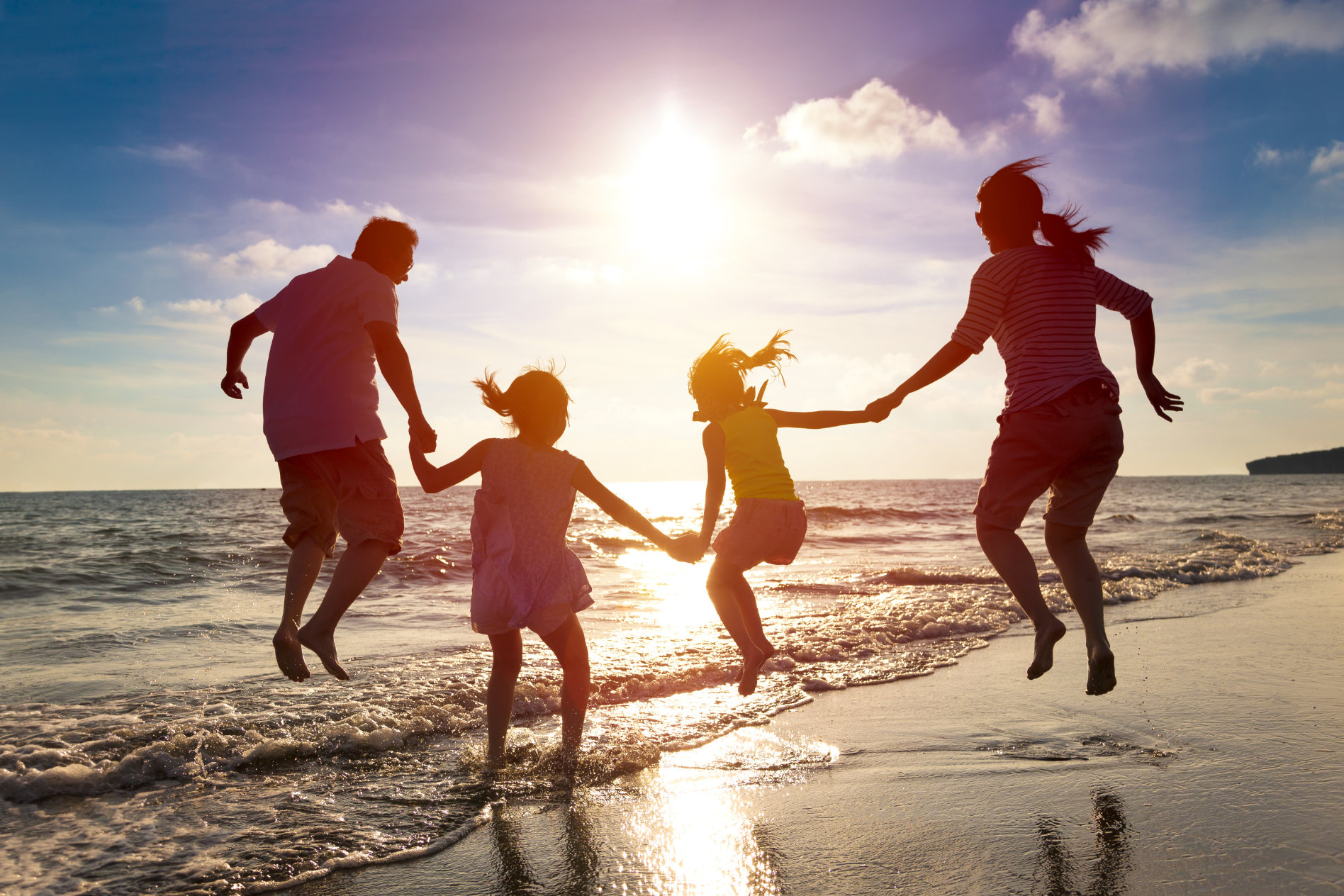 A family jumping on the beach.